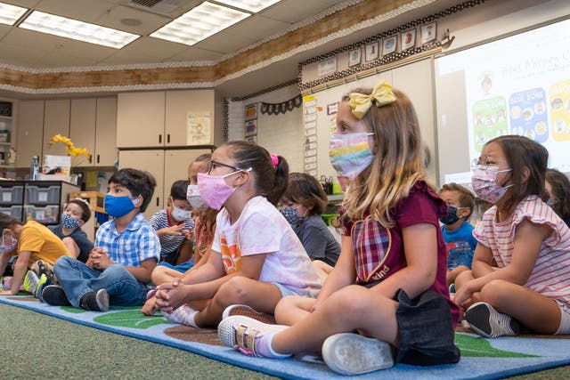 Los estudiantes escuchan a su maestro durante su primer día de kínder de transición en la escuela primaria Tustin Ranch en Tustin, California, el 12 de agosto de 2021