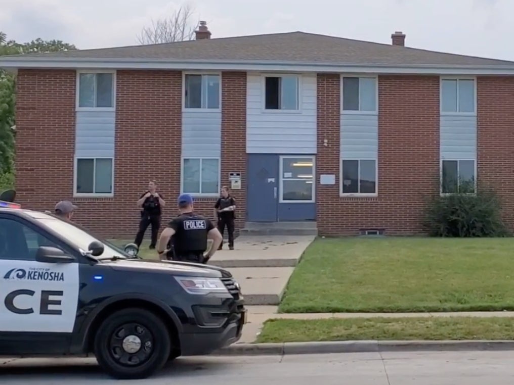 Police wait outside an apartment where a 19-year-old woman accidentally shot a 21-year-old man in the leg with a gun after she used the firearm’s laser sight to play with a cat