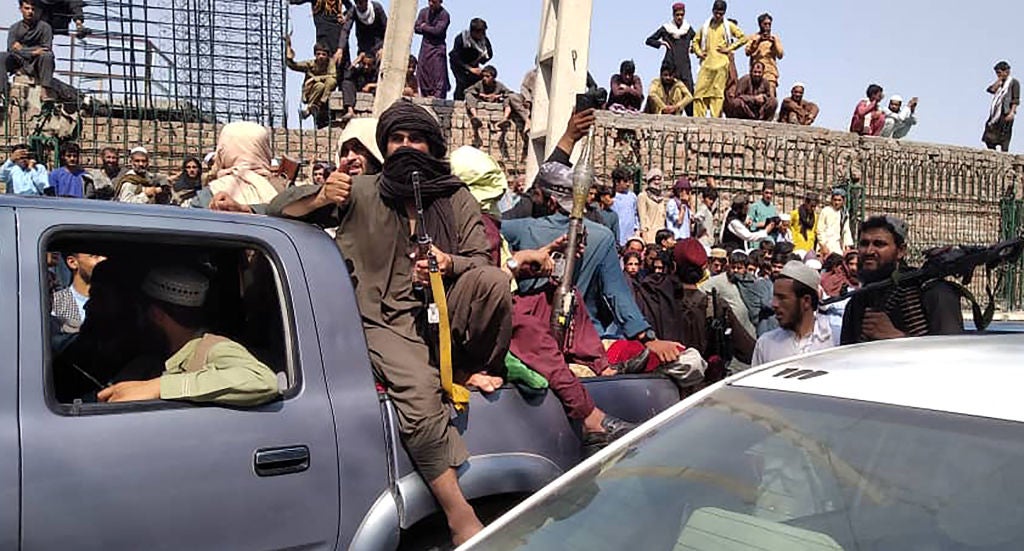 <p>Taliban fighters sit on a vehicle on the street in Jalalabad province on 15 August</p>