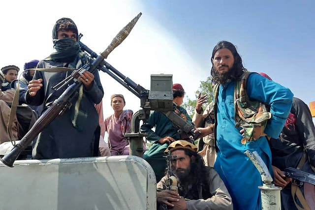 <p>Taliban fighters sit over a vehicle on a street in Laghman province</p>