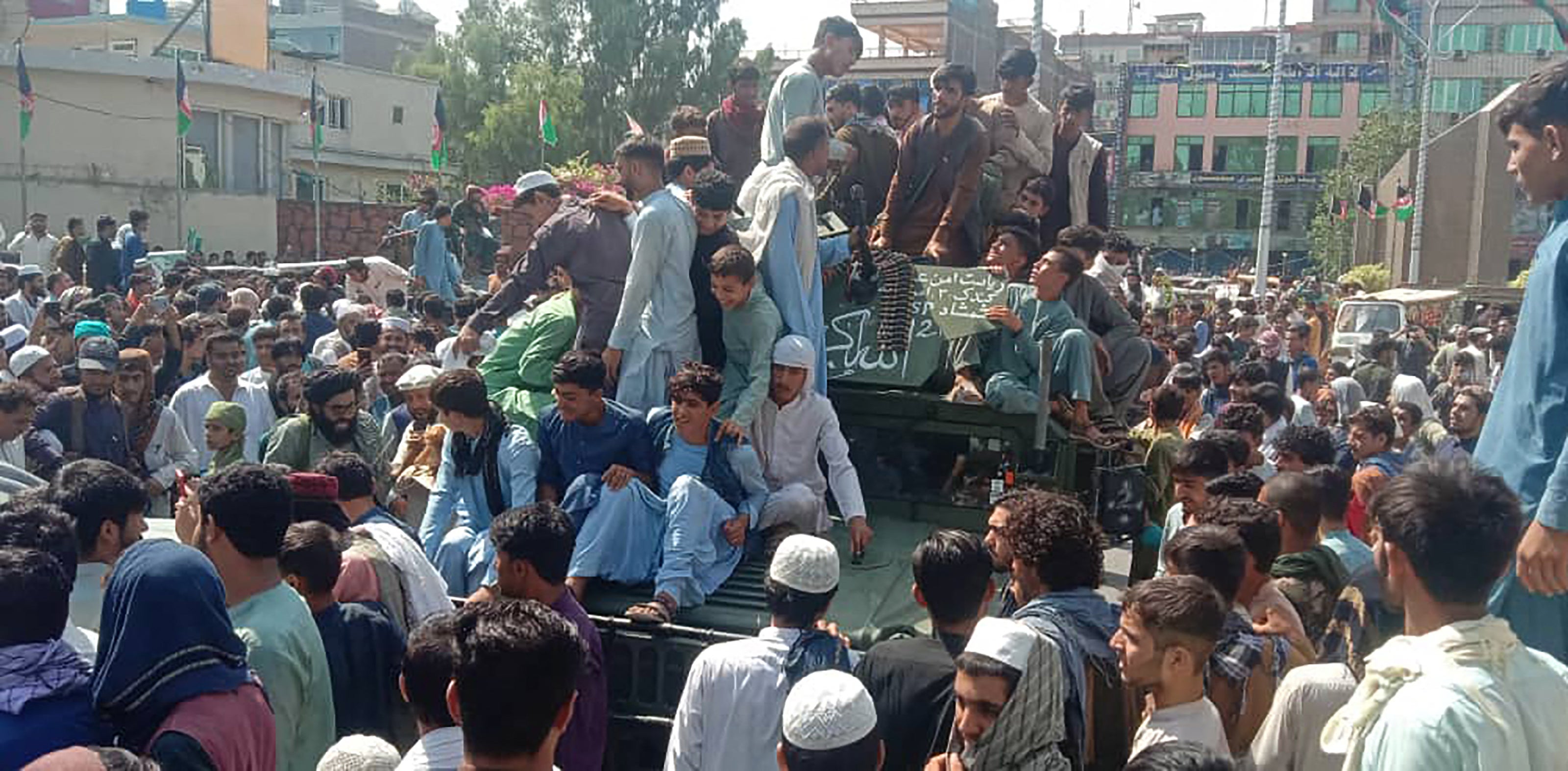 Taliban fighters and local people sit on an Afghan National Army humvee on a street in Jalalabad province on 15 August