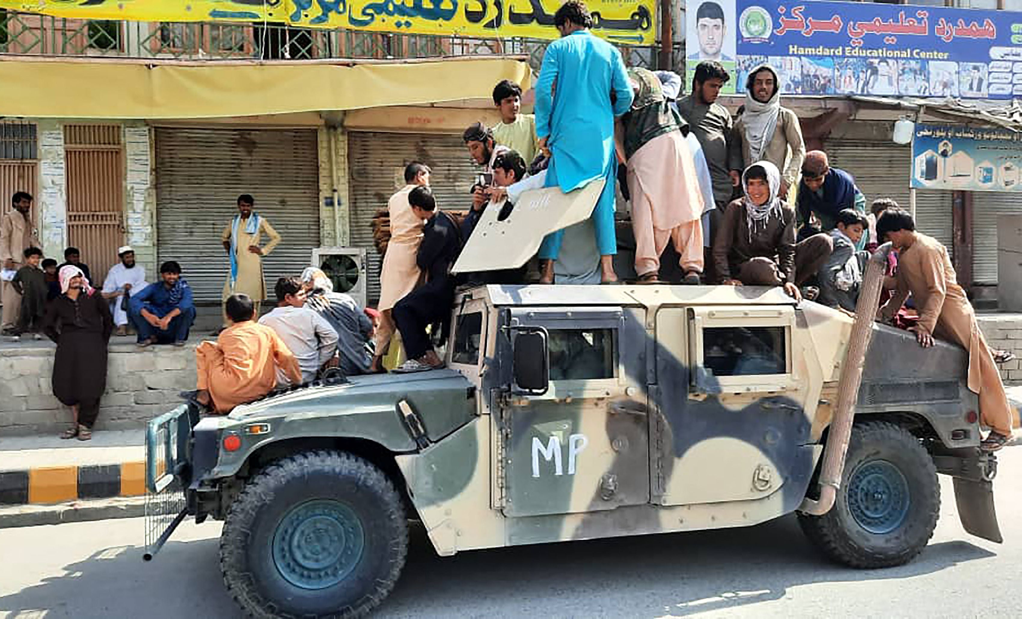 Taliban fighters and local residents sit over an Afghan National Army