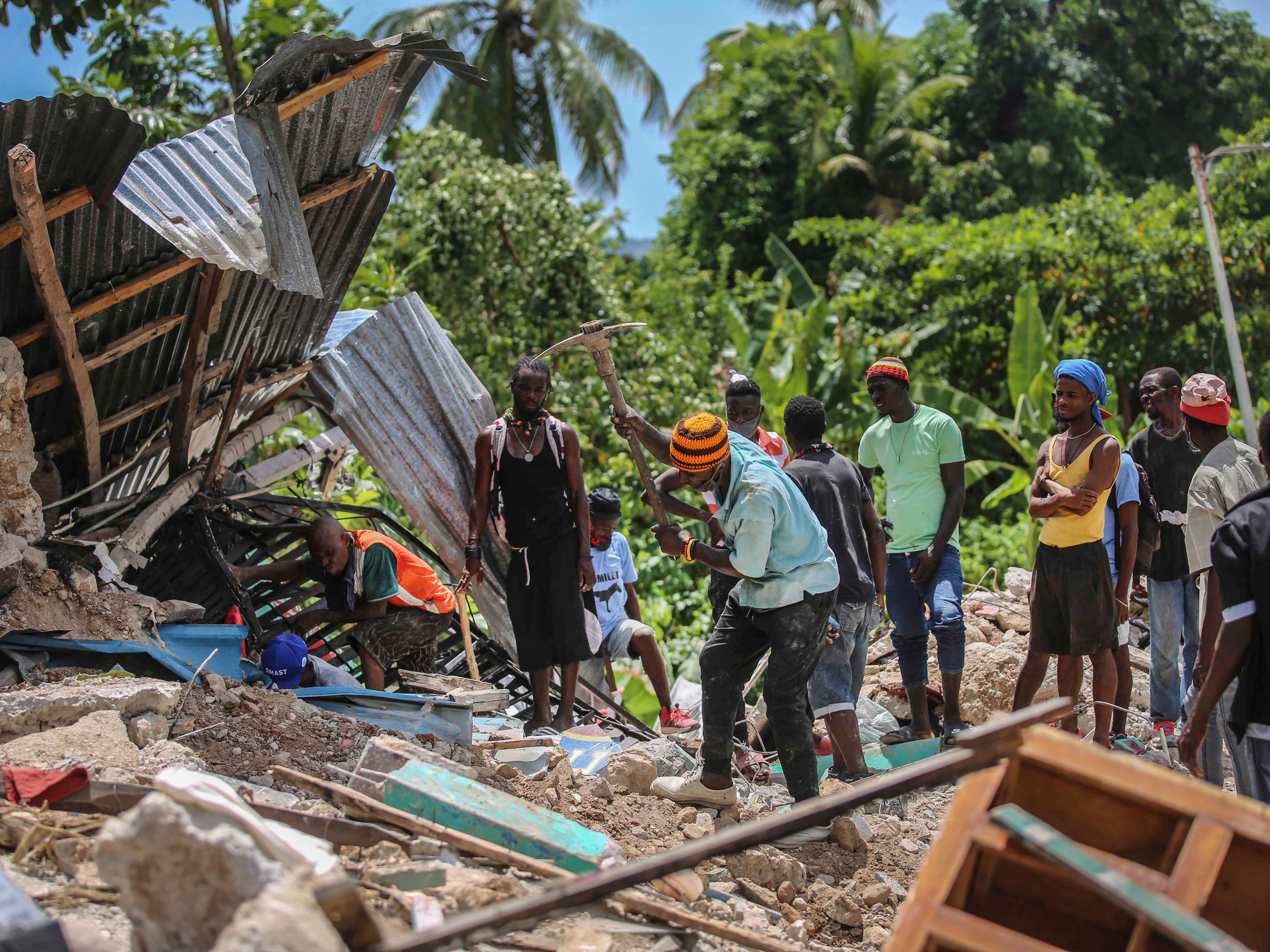 Locals search for victims in a home destroyed by an earthquake in Les Cayes
