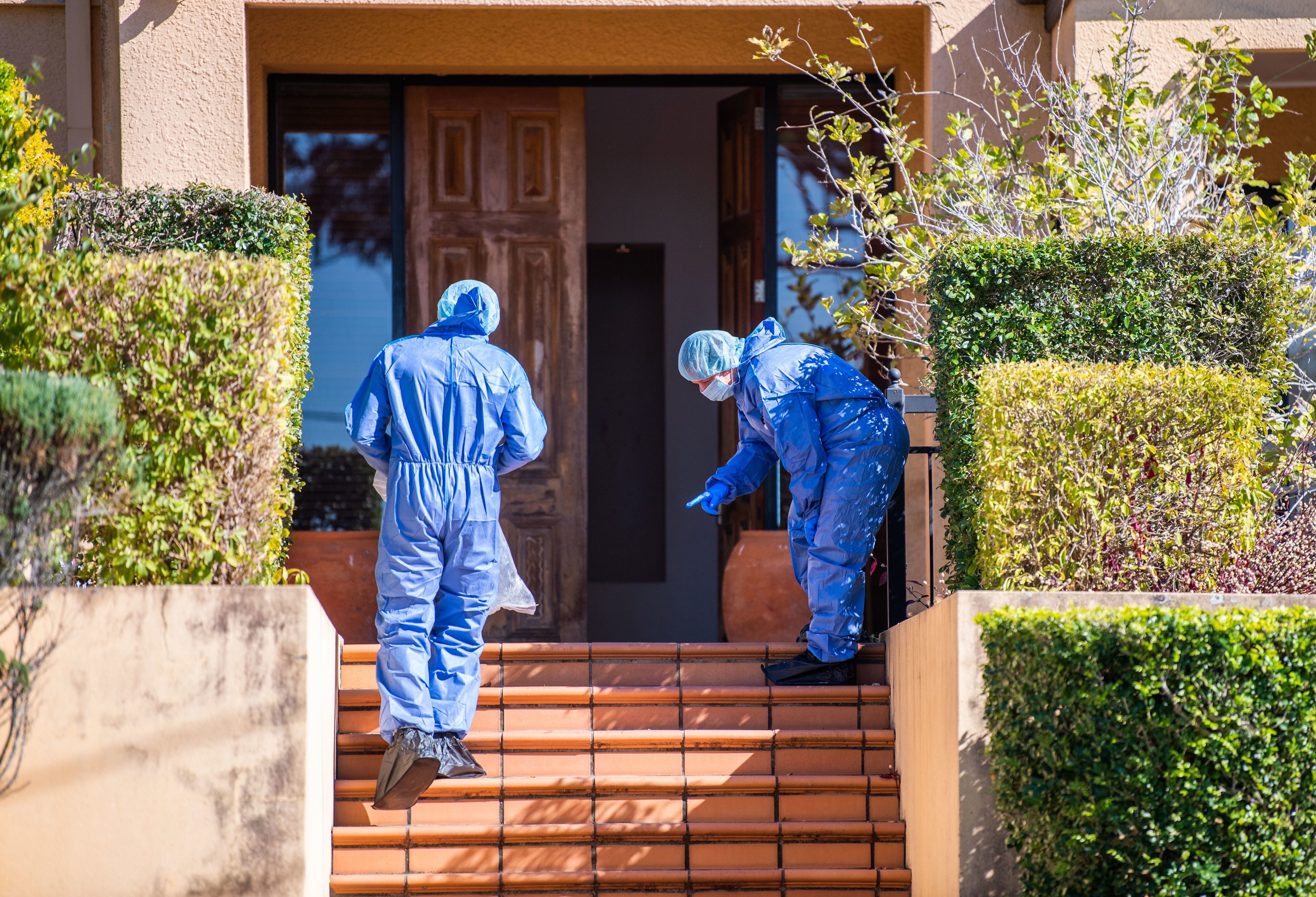 Police forensics officers examine the scene of the violent home invasion