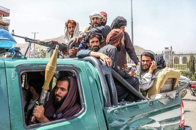 Combatientes talibanes son vistos en la parte trasera de un vehículo en Kabul, Afganistán