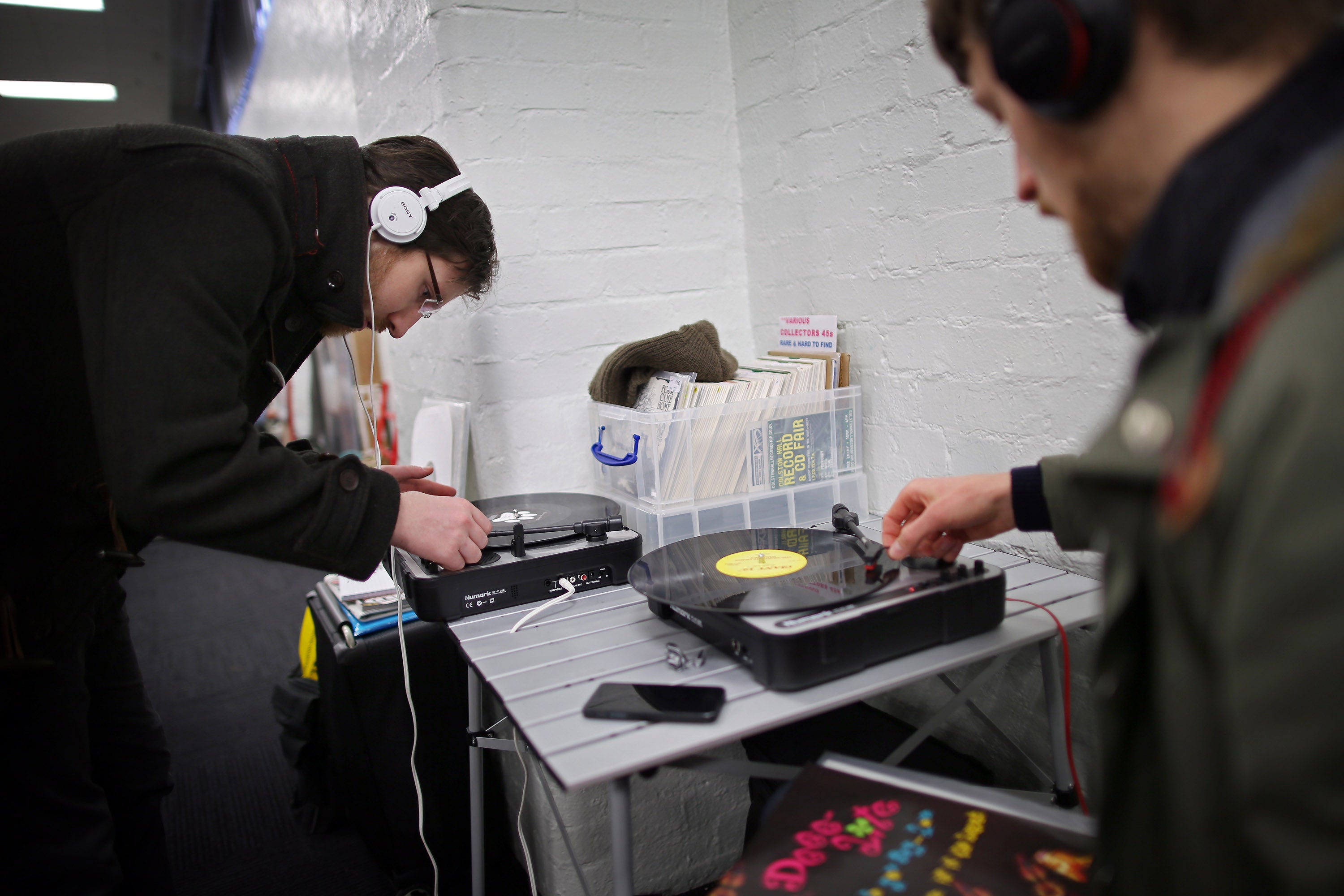 Customers play albums on portable turntables at the Olympia record fair. There is an innate human desire to own a tangible object