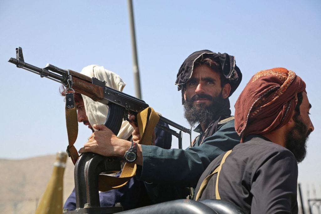 File: Taliban fighters stand guard in a vehicle along the roadside in Kabul