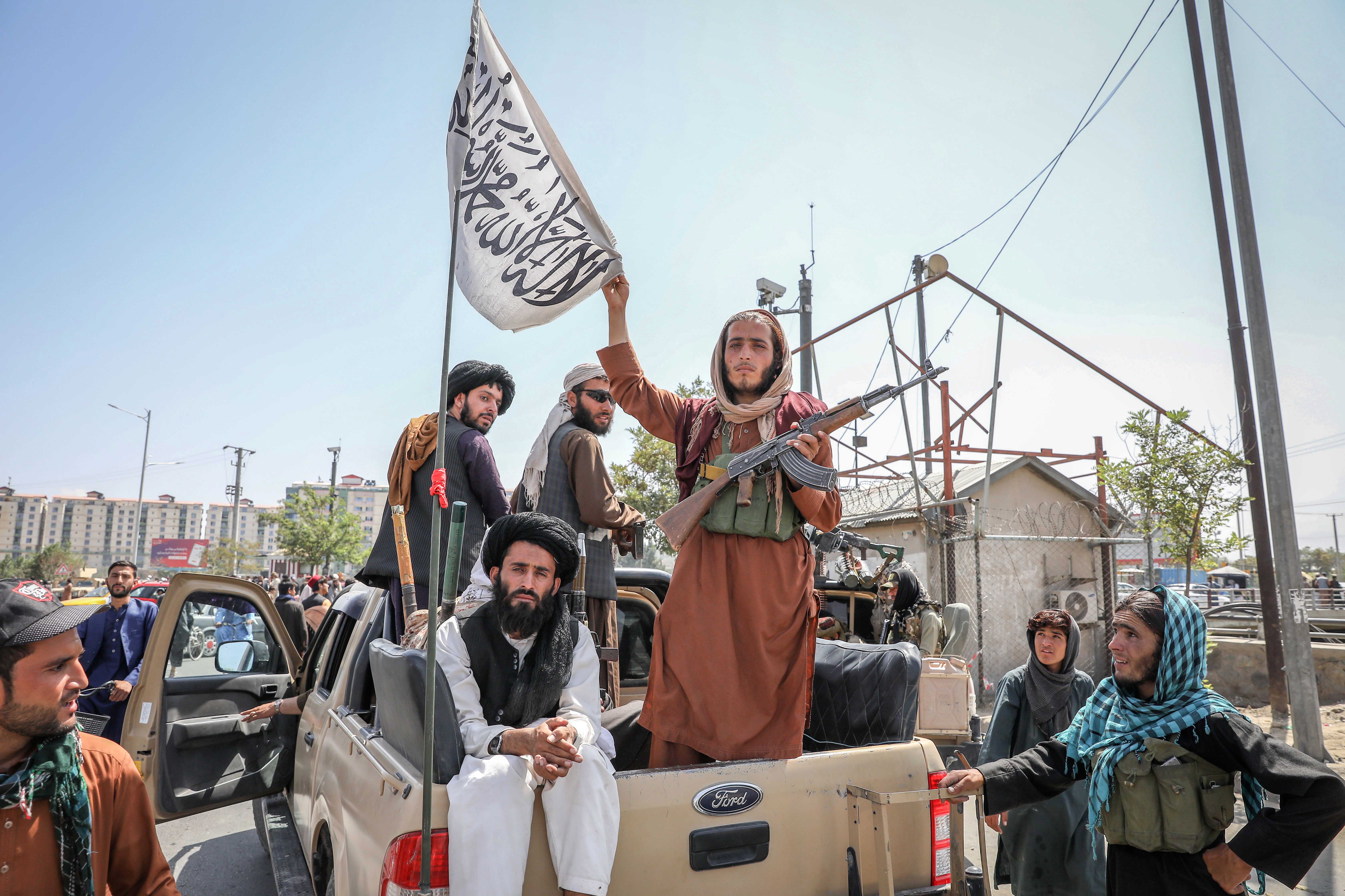 Taliban fighters are seen on the back of a vehicle in Kabul, Afghanistan