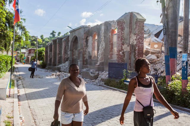 <p> People walk by the collapsed Notre-Dame du Perpetuelle Secour church after a 7.2-magnitude earthquake struck Haiti on Saturday.</p>