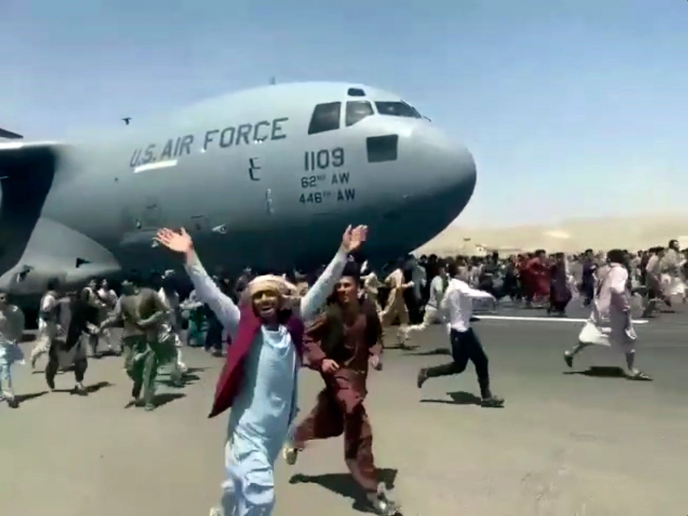 Hundreds of people run alongside a US Air Force C-17 transport plane as it moves down a runway of the international airport in Kabul