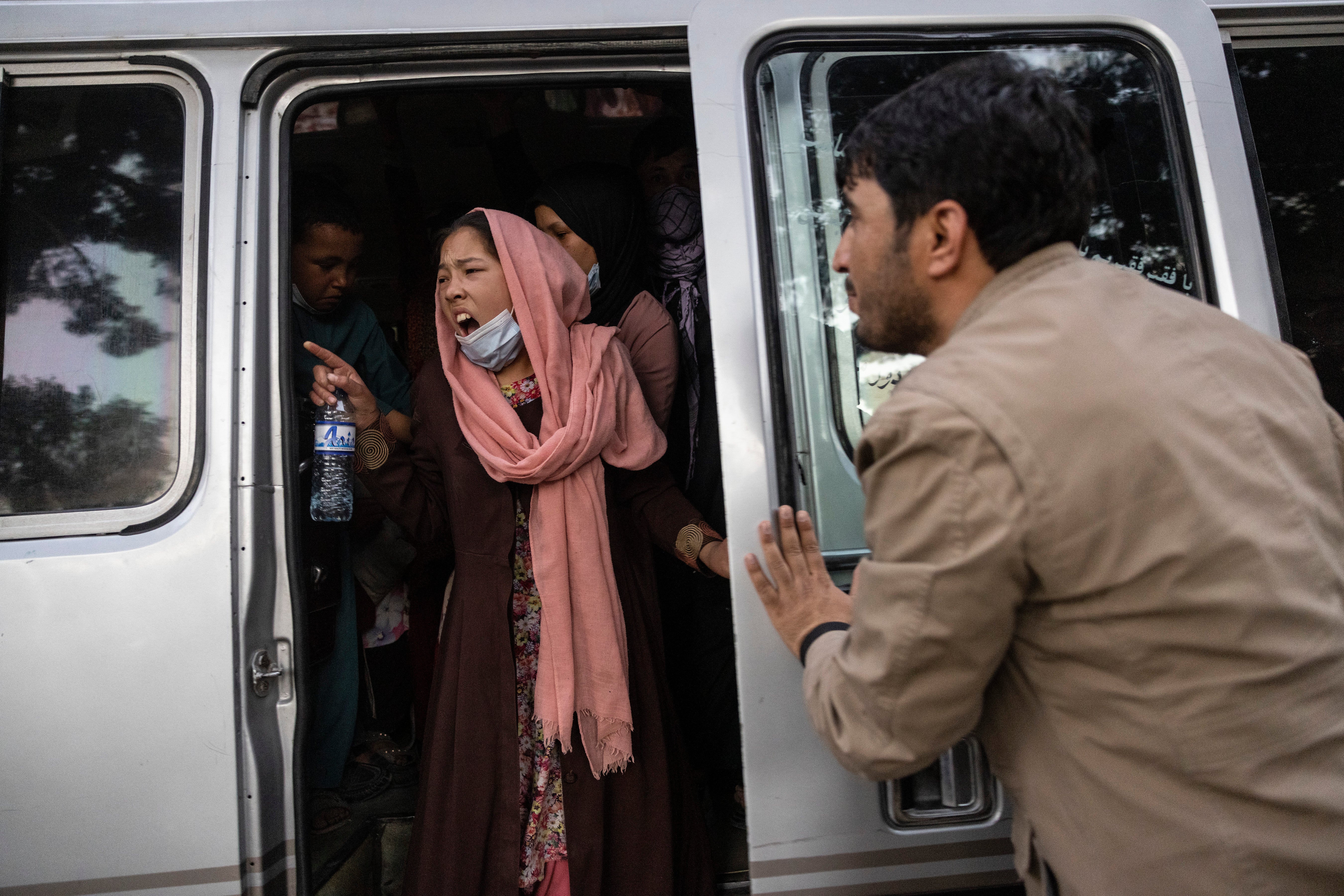 Woman urges her family to hurry up as displaced Afghans from northern part of country are evacuated from camp to Kabul