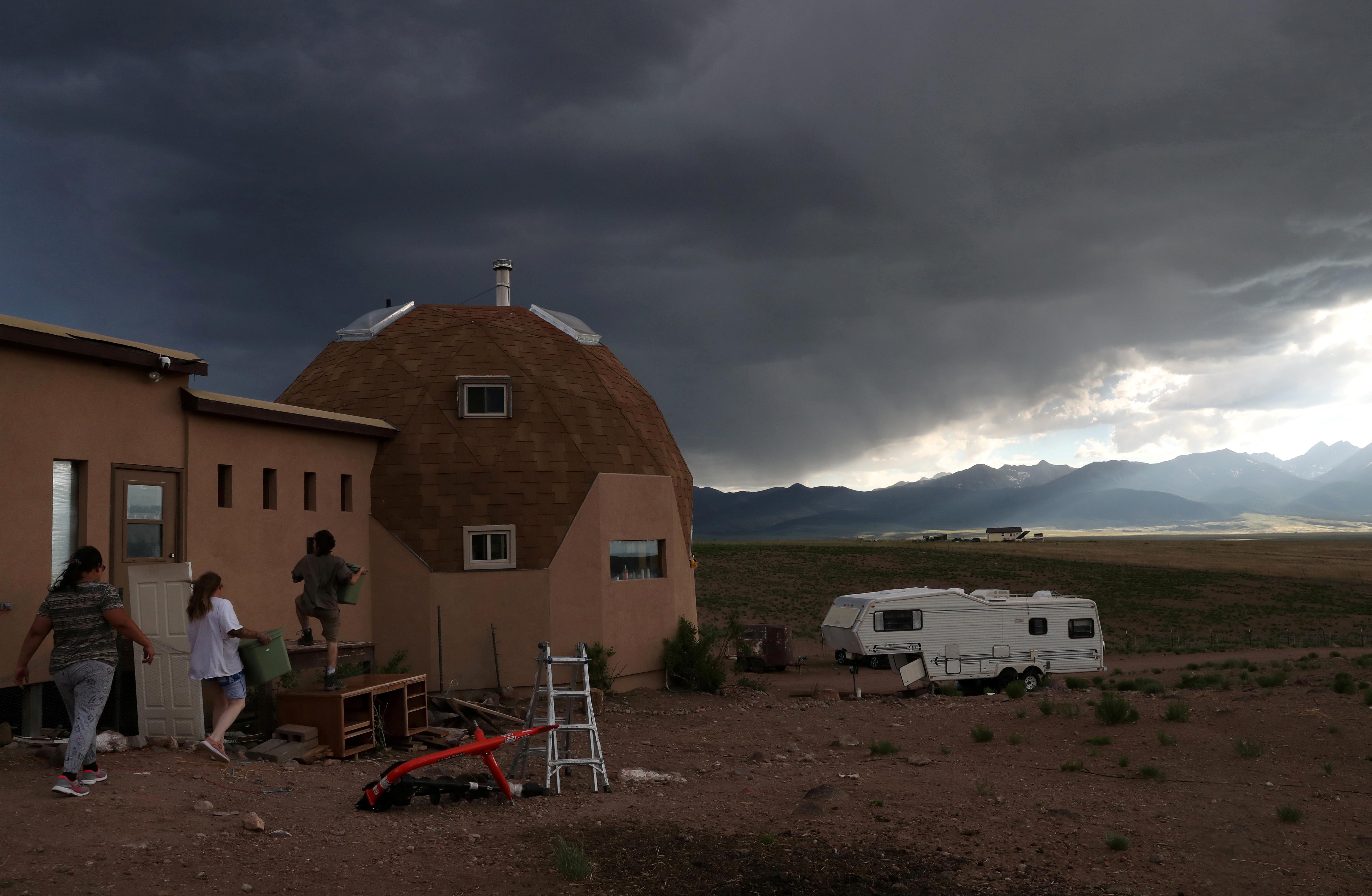 Ranch members Bonnie Nelson, 34, and Penny Logue, 40, get help bringing in items from volunteers after a long day of shearing ahead of an incoming storm