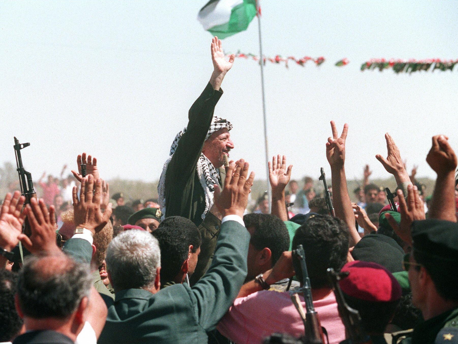 PLO chairman Yasser Arafat waves to a crowd of cheering Palestinians after he crossed the Rafah border point on 1 July 1994, entering the newly self-ruled Gaza Strip for the first time in 27 years