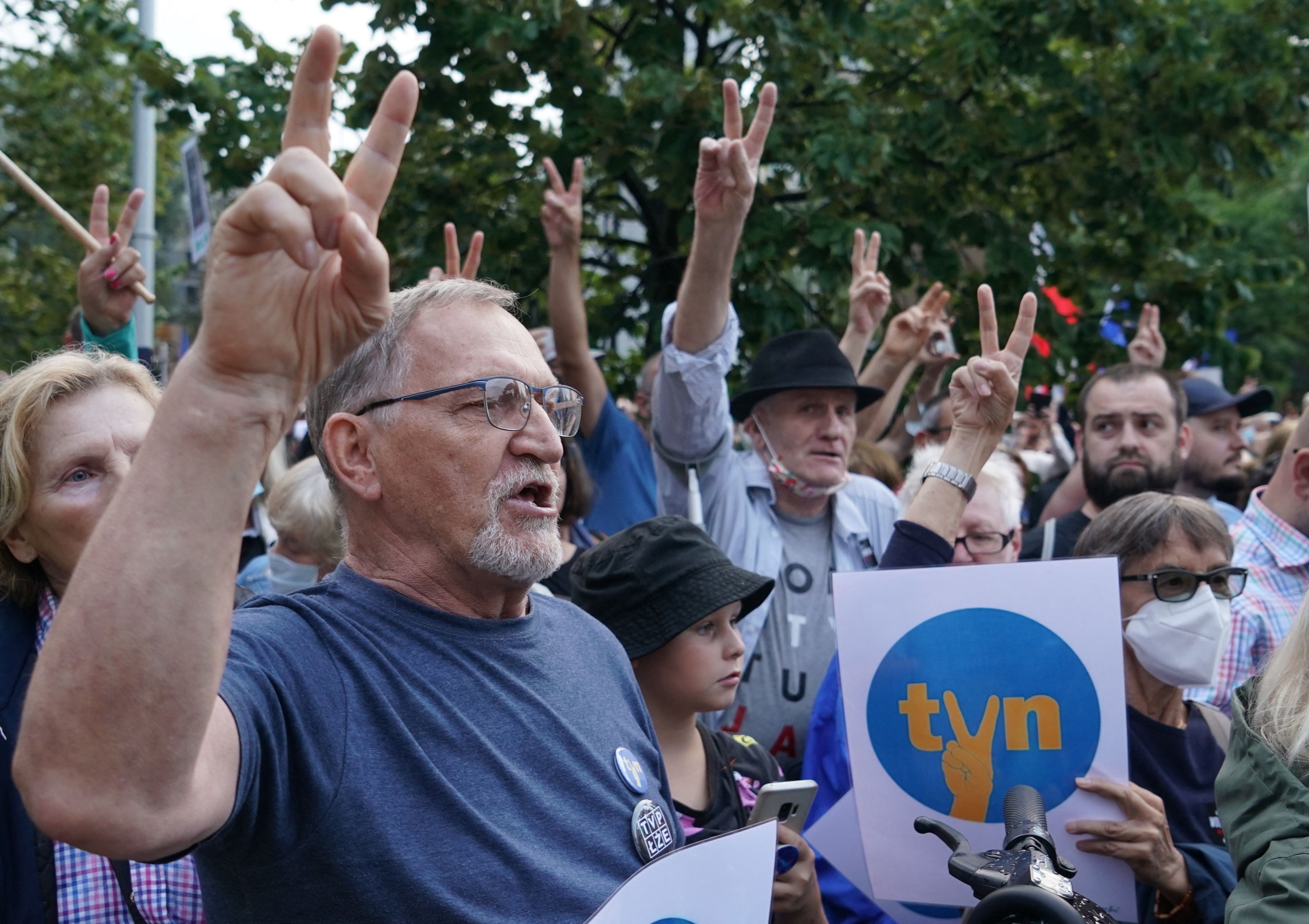 Protesters show the victory sign as they hold up placards with the letters of Poland's main private TV network TVN, a US-owned broadcaster, as they demonstrate in defence of media freedom in Warsaw