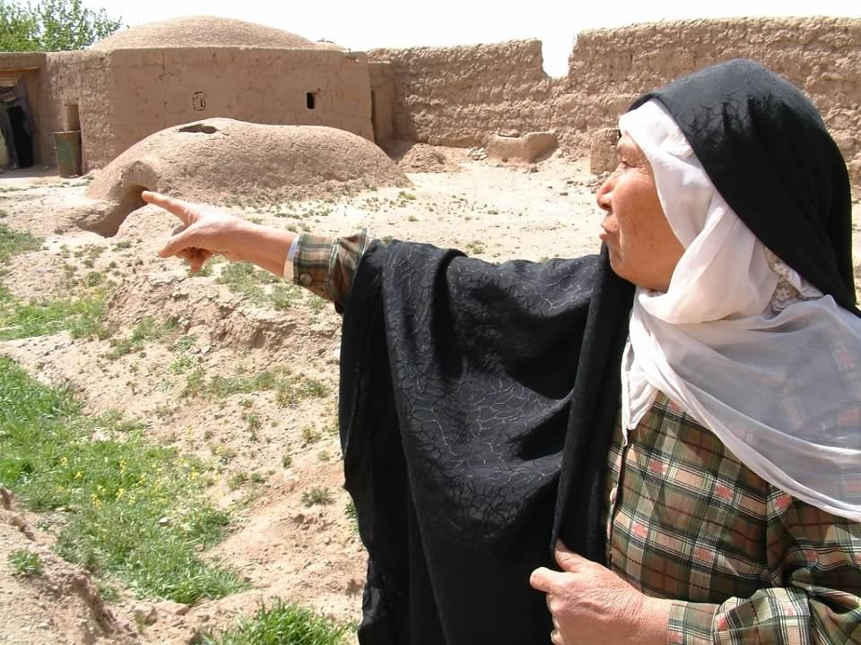 An Afghan woman points to the location of an airstrike that struck her home in the western city of Herat in 2002