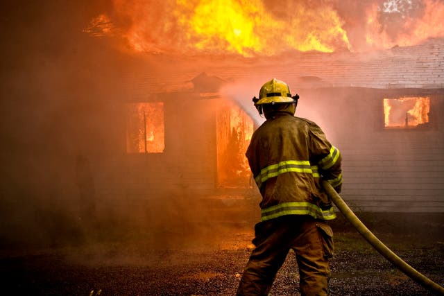 <p>A fireman attempts to stop a house from burning down (file photo) </p>