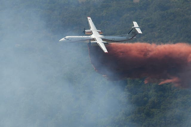 <p>A plane drops fire retardant onto a smoking forest fire on a  hillside near Grimaud, in the department of Var, southern France</p>