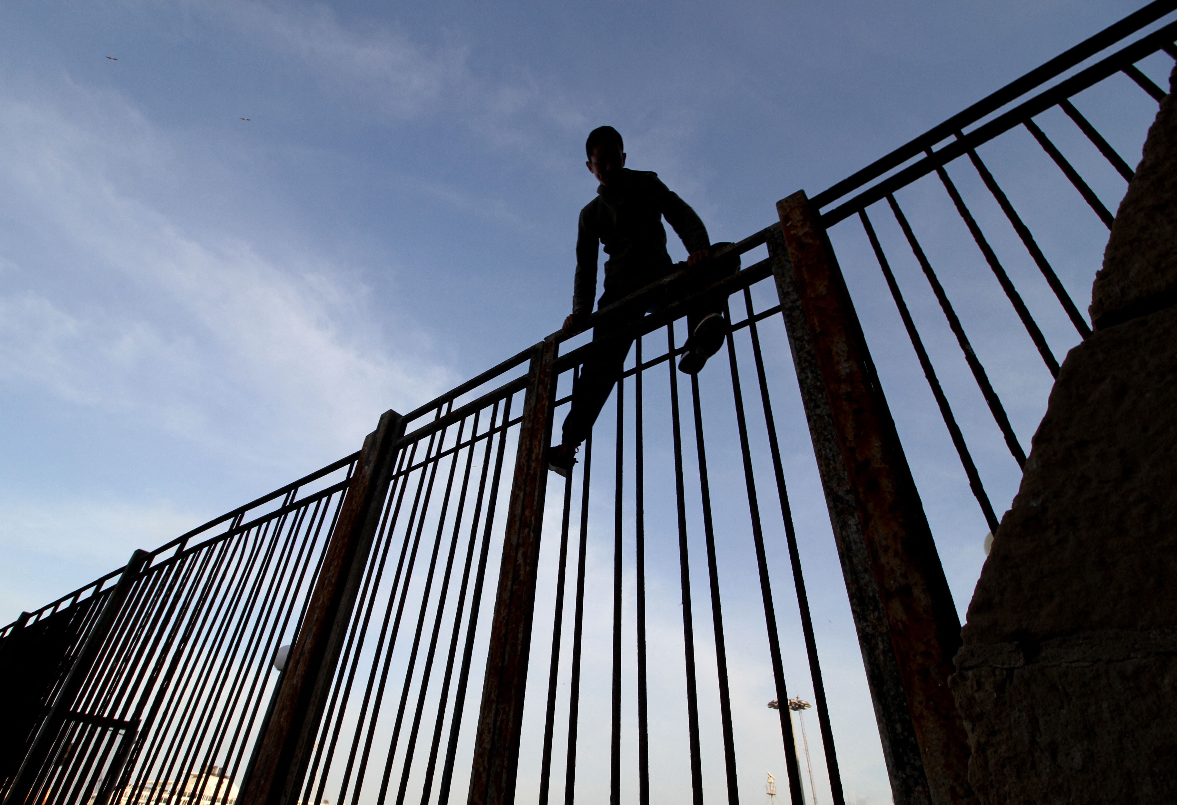 A Moroccan boy climbs a fence in the port of the Spanish enclave of Melilla