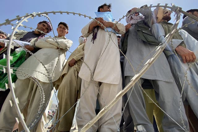 <p>Afghans, including those who worked for the US, Nato, the EU and the UN in Afghanistan, wait outside the Hamid Karzai International Airport to flee the country</p>