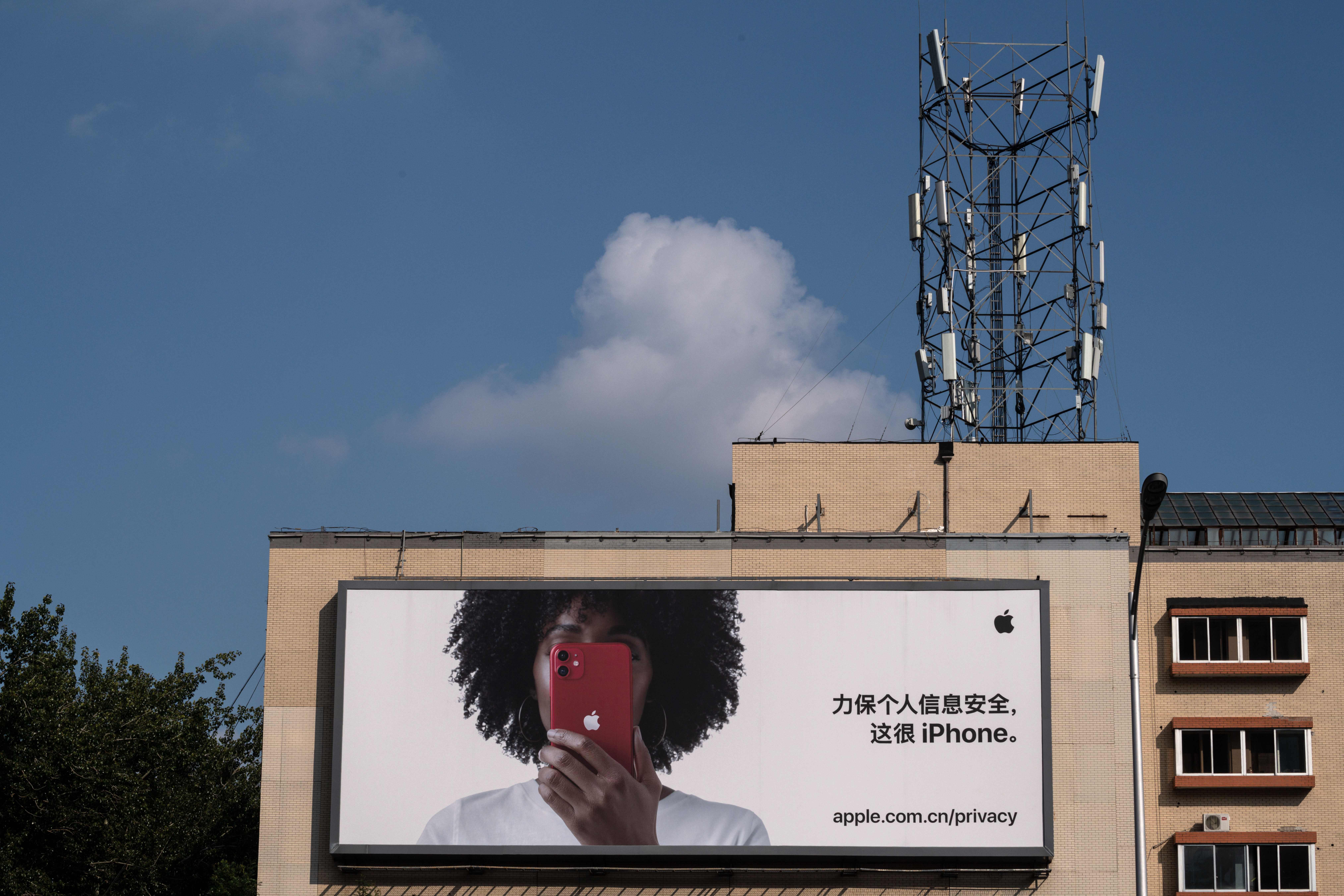 <p>A cellphone tower on top of a building is seen next to a commercial billboard for the iPhone in Beijing</p>