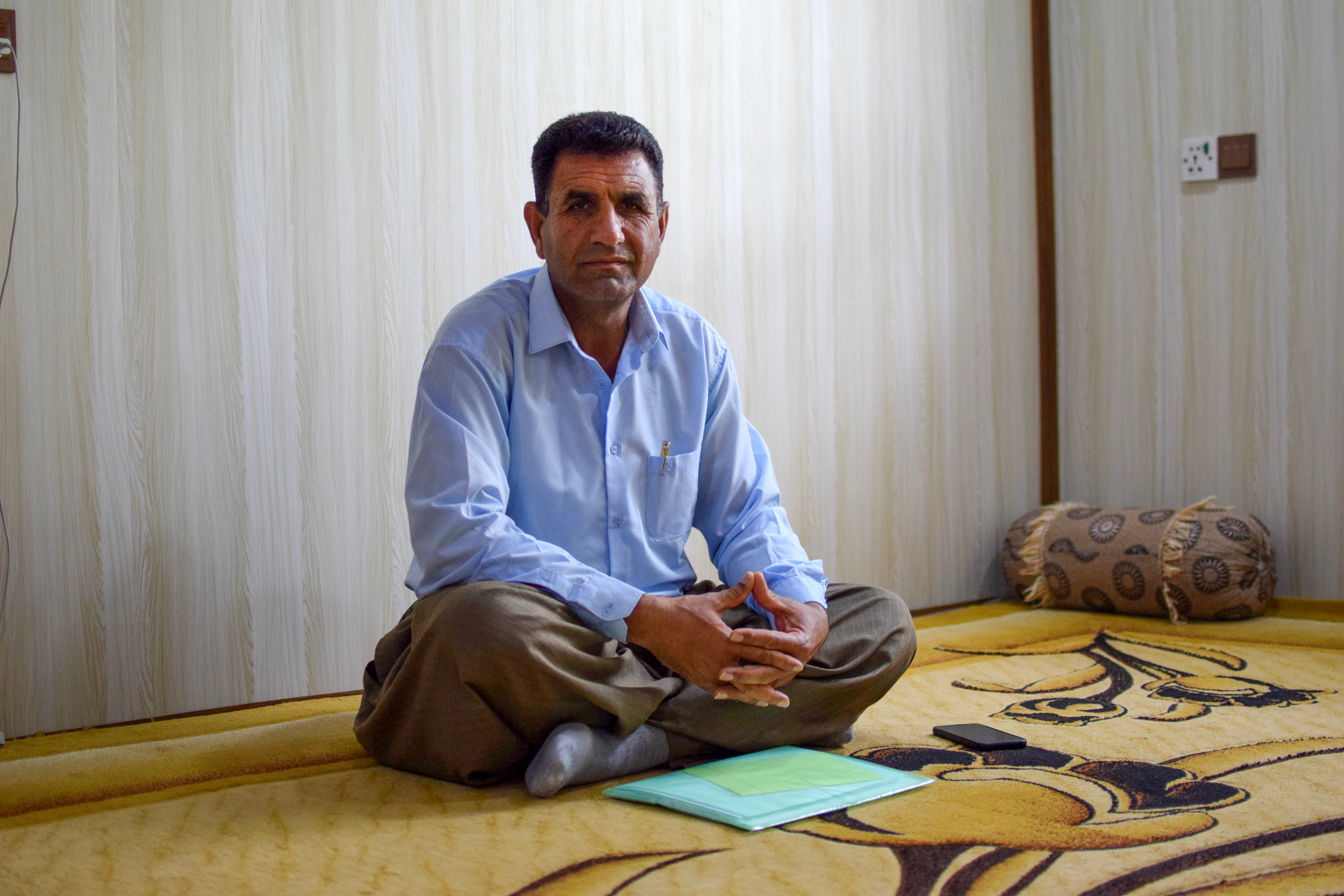 Iranian Kurdish refugee Husein Karimi sits with a folder of precious documents in his living room in the Barika refugee camp in the Kurdistan Region of Iraq in April 2021