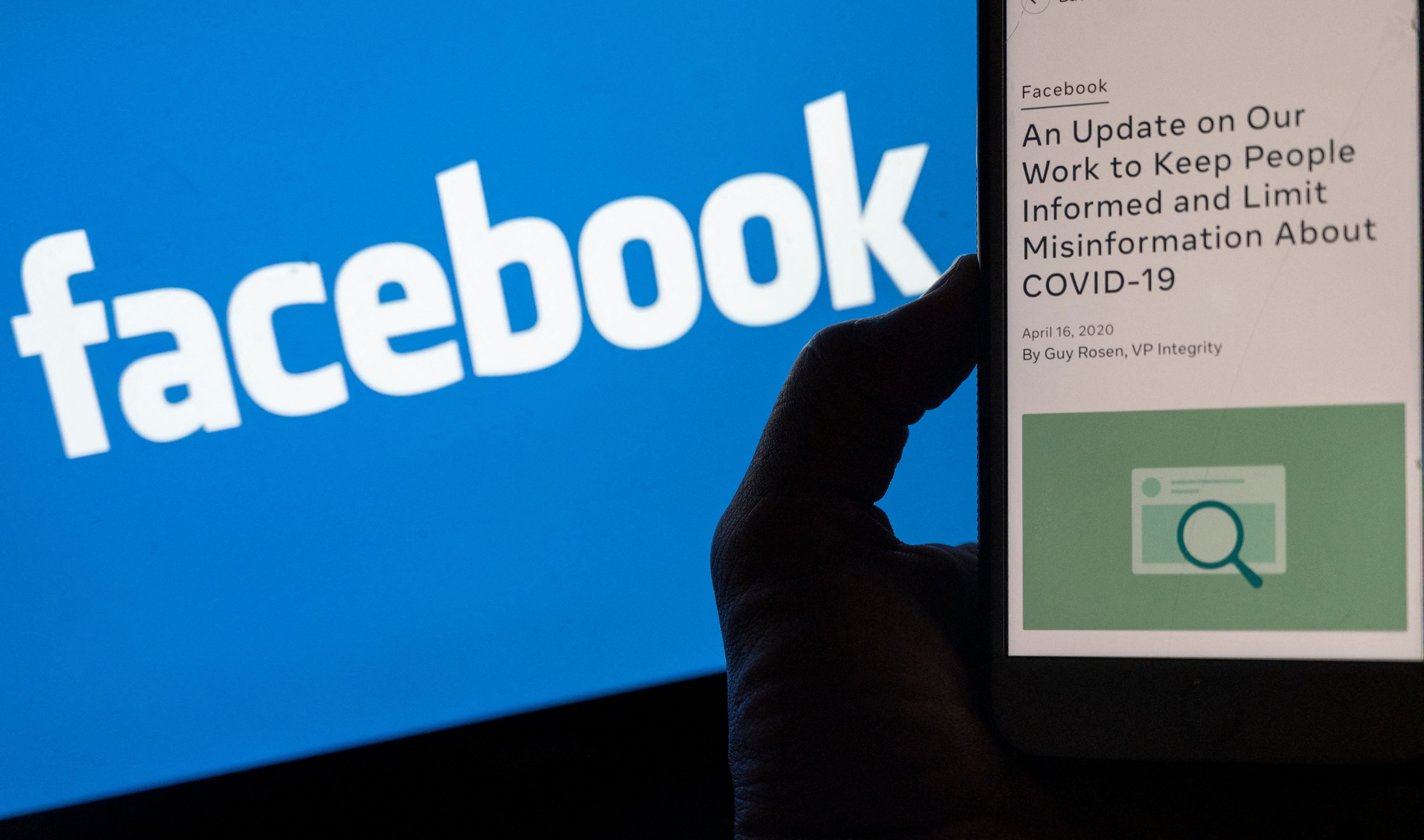 Smart phone screen displays a new policy on Covid-19 misinformation with a Facebook website in the background