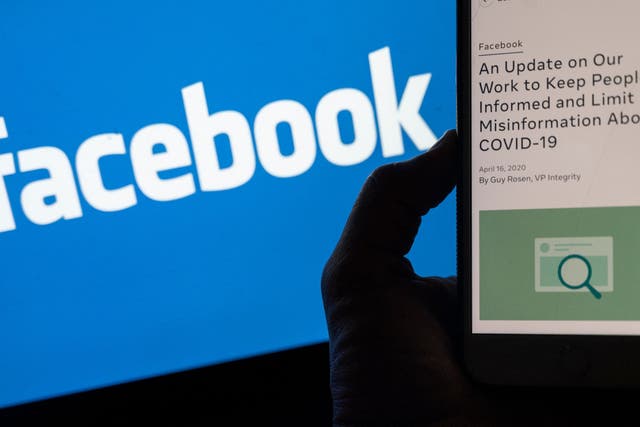 <p>Smart phone screen displays a new policy on Covid-19 misinformation with a Facebook website in the background</p>