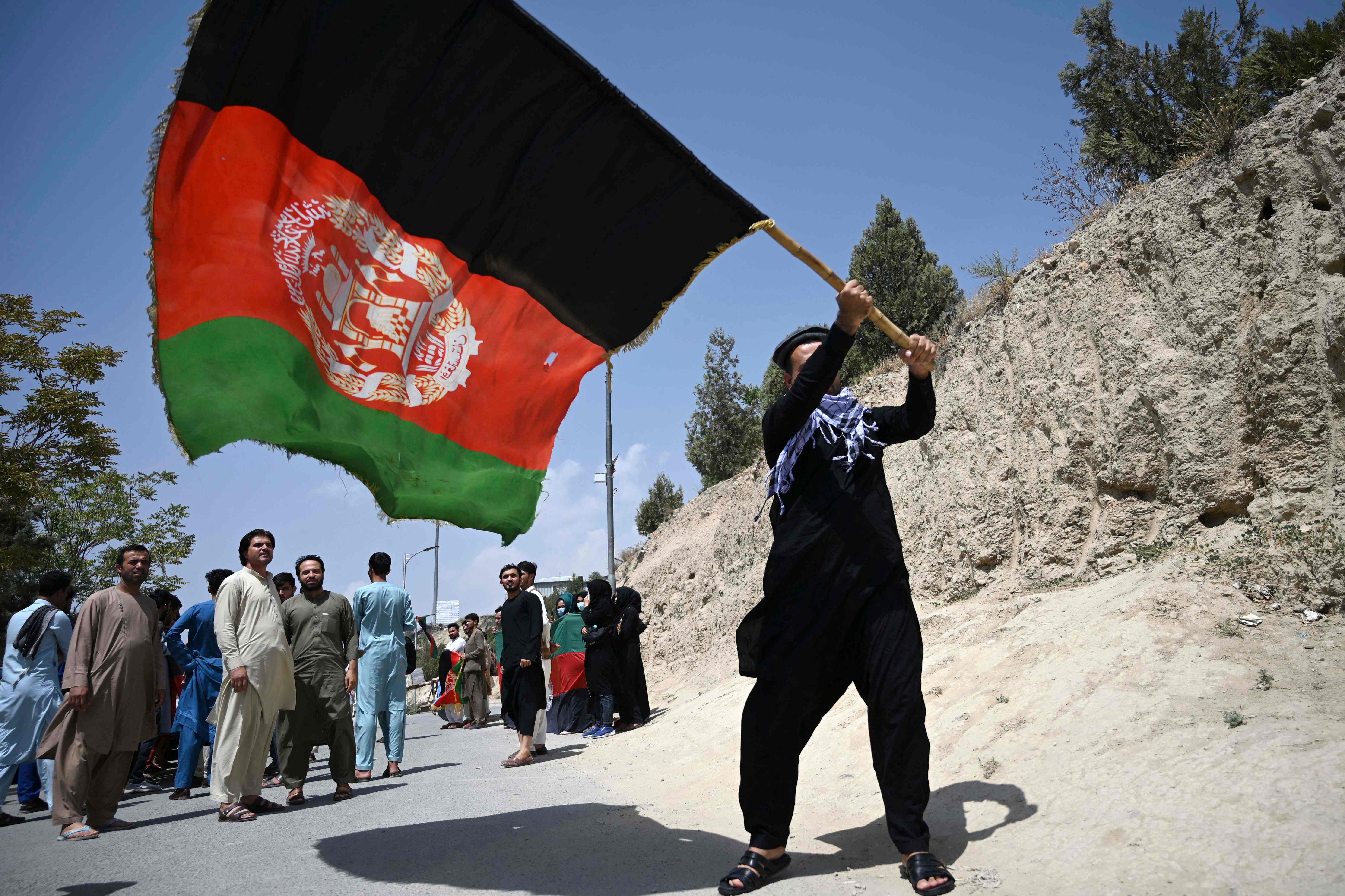 An Afghan waves the national flag as they celebrate the 102nd Independence Day of Afghanistan in Kabul on 19 August 2021
