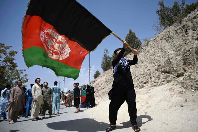 <p>An Afghan waves the national flag as they celebrate the 102nd Independence Day of Afghanistan in Kabul on 19 August 2021</p>