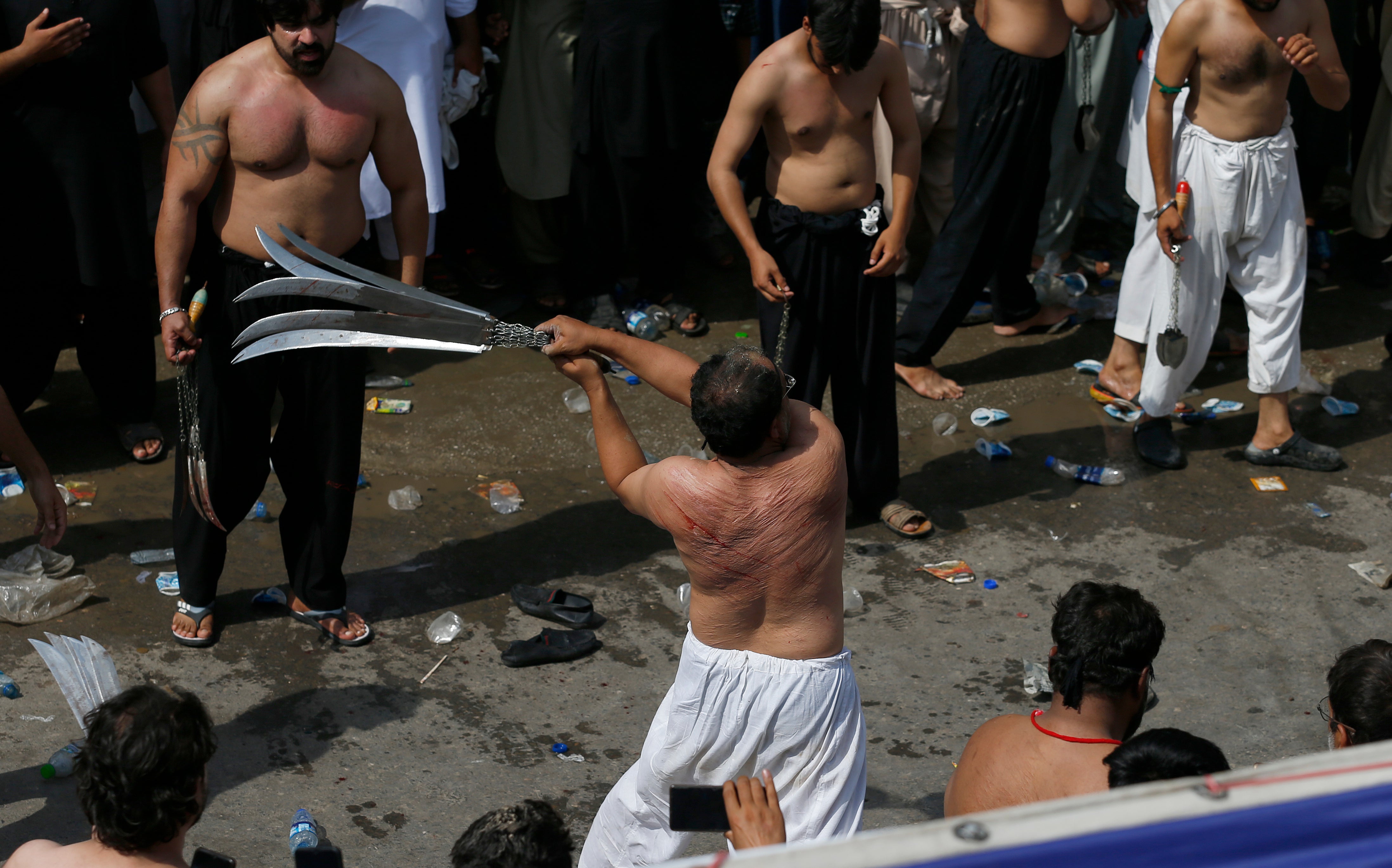 A Shia Muslim flagellates himself with swords on chains during a procession to mark Ashura in Rawalpindi, Pakistan on 19 August 2021