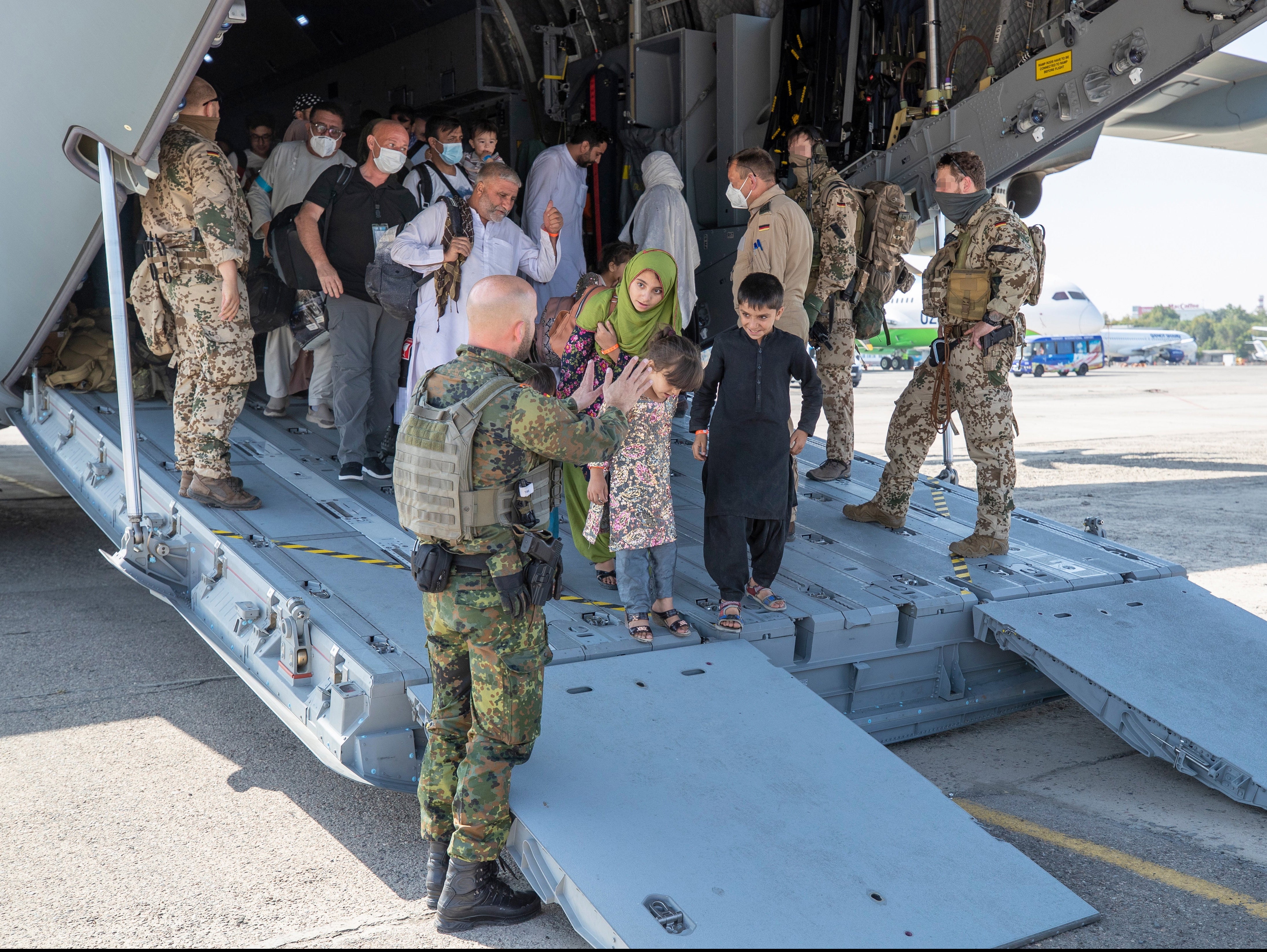 German soldiers talk to evacuees upon arrival from Kabul on board a German air force plane at Tashkent airport, Uzbekistan, 18 August 2021