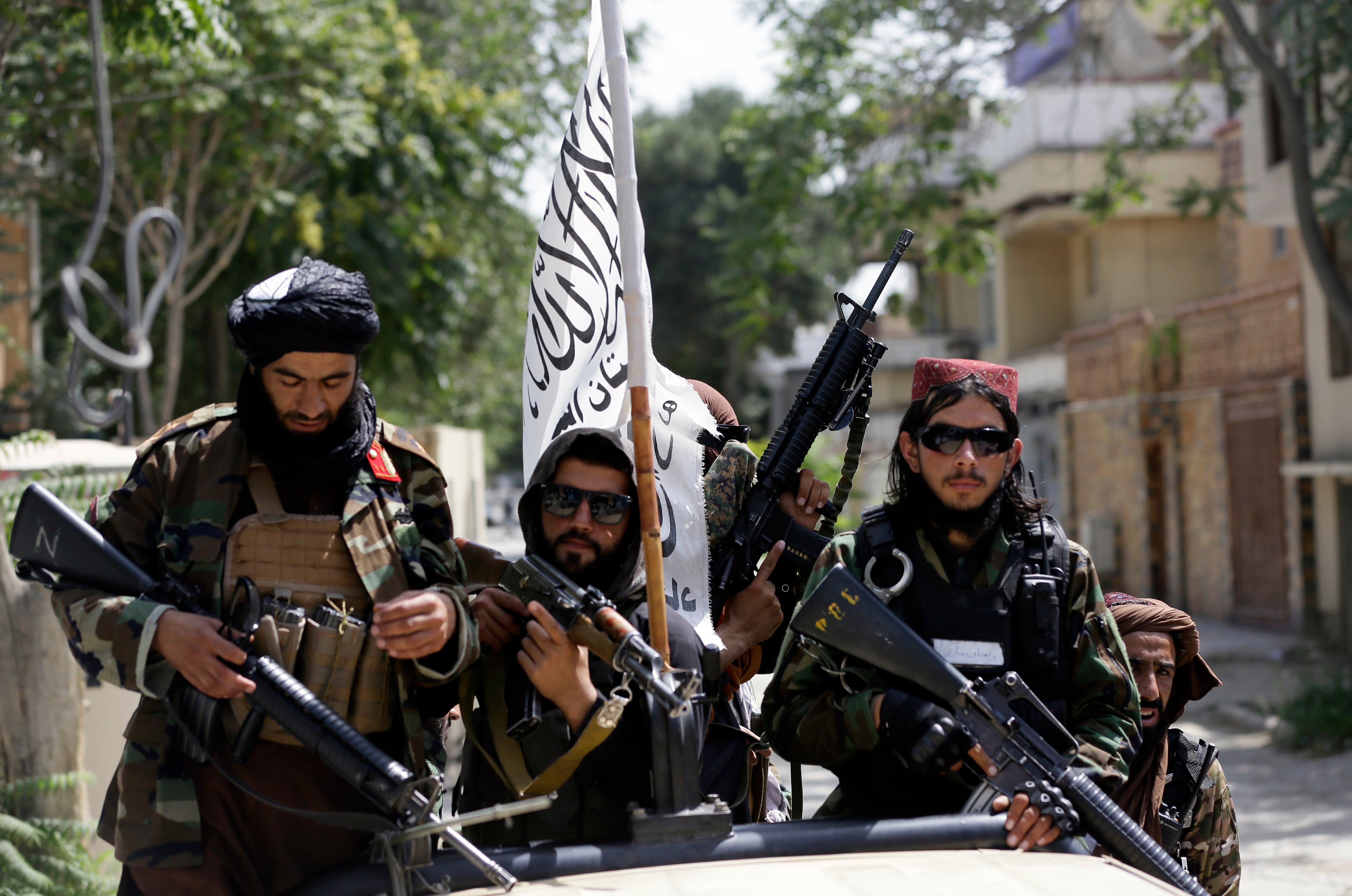 Taliban fighters display their flag on patrol in Kabul, 19 August 2021