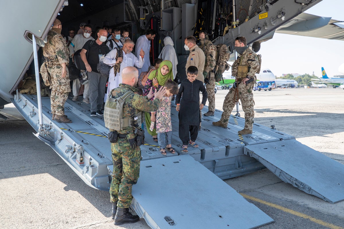 German soldiers talk to evacuees upon arrival from Kabul on board a German air force plane at Tashkent airport, Uzbekistan