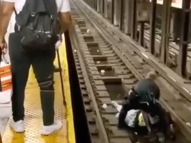 Un oficial de la policía de Nueva York en las vías del metro en el Bronx ayudando a un hombre que se desmayó y cayó en el camino de un tren subterráneo que se aproximaba. El hombre fue rescatado gracias al oficial de policía y un buen samaritano.