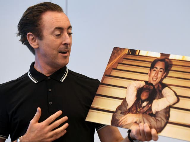 <p>Actor Alan Cumming speaks while holding a photograph of himself with Tonka, his chimpanzee co-star from the 1997 film ‘Buddy’ during an announcement on June 23, 2017</p>