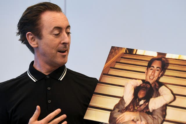 <p>Actor Alan Cumming speaks while holding a photograph of himself with Tonka, his chimpanzee co-star from the 1997 film ‘Buddy’ during an announcement on June 23, 2017</p>