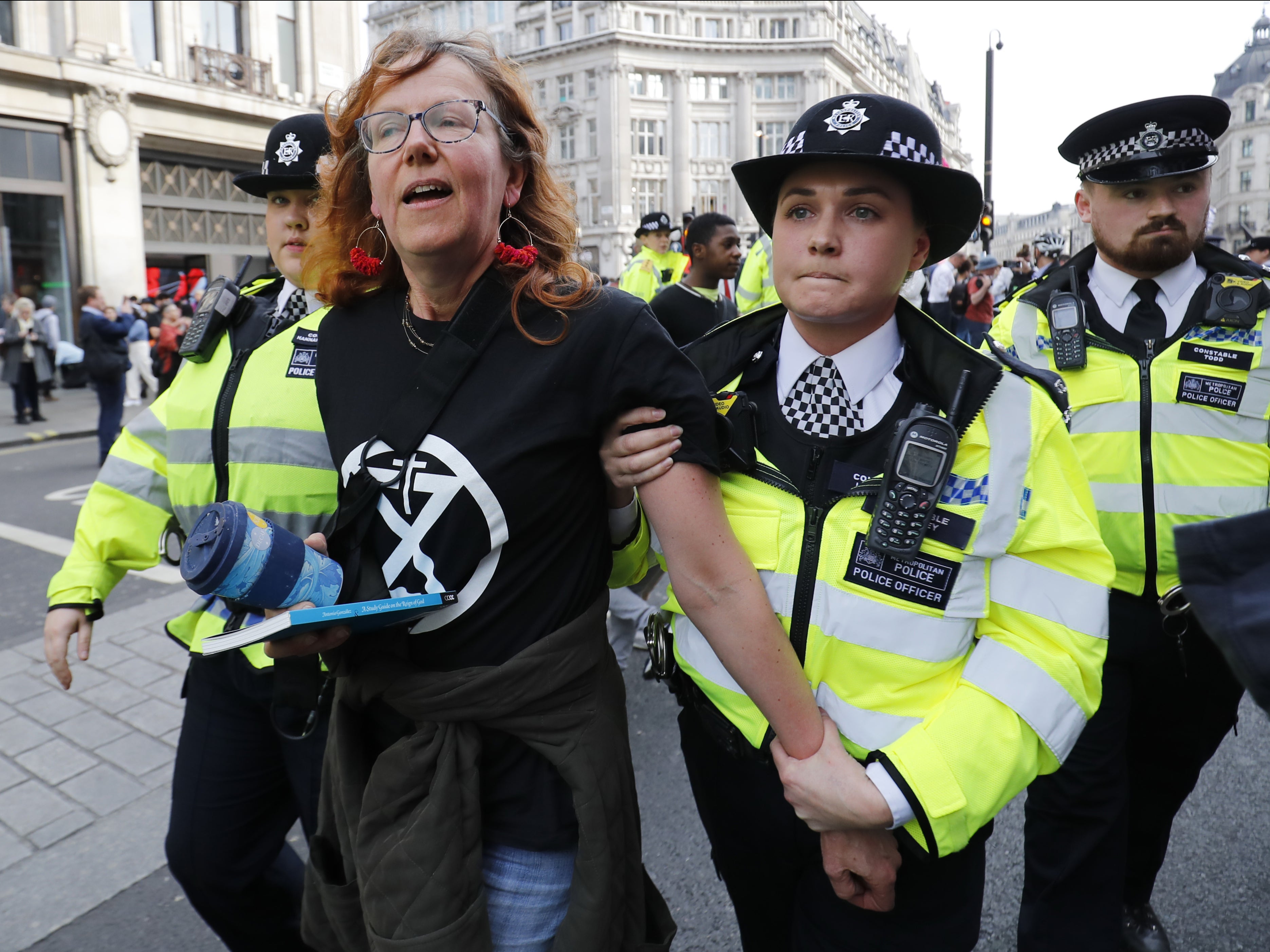 Police officers escorting a climate activist during protests in April 2019
