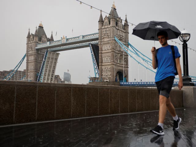 <p>A man is pictured walking in the rain by London’s Tower Bridge earlier this month </p>