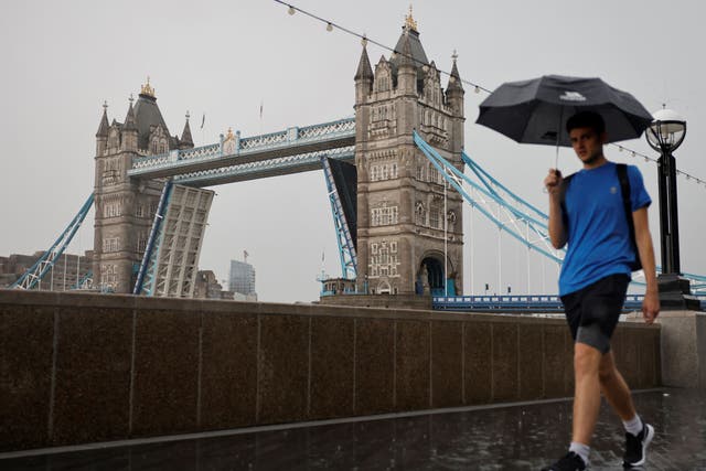 <p>A man is pictured walking in the rain by London’s Tower Bridge earlier this month </p>