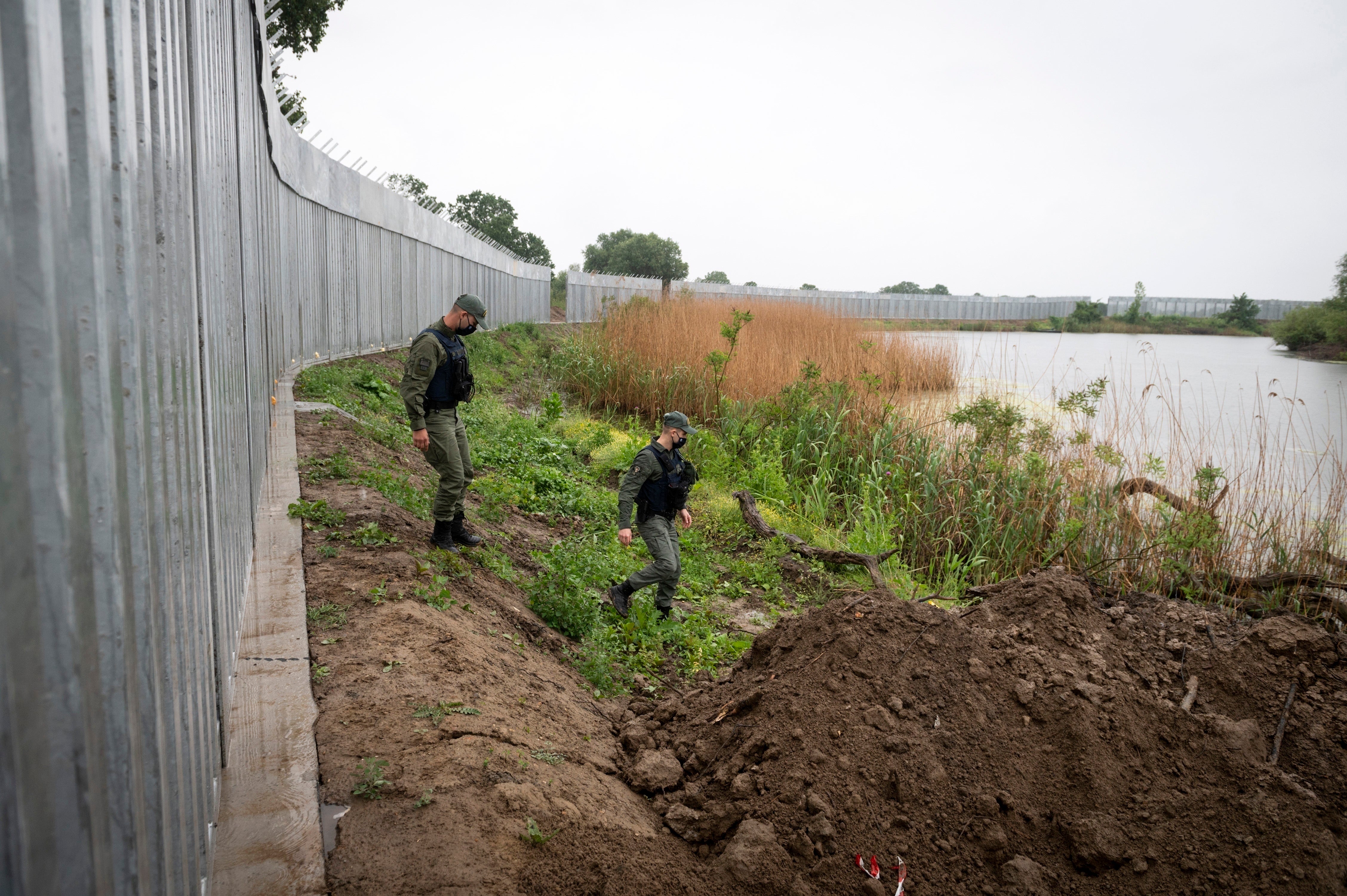 Police patrol a steel wall at Evros river near the village of Poros at the Greece-Turkey border