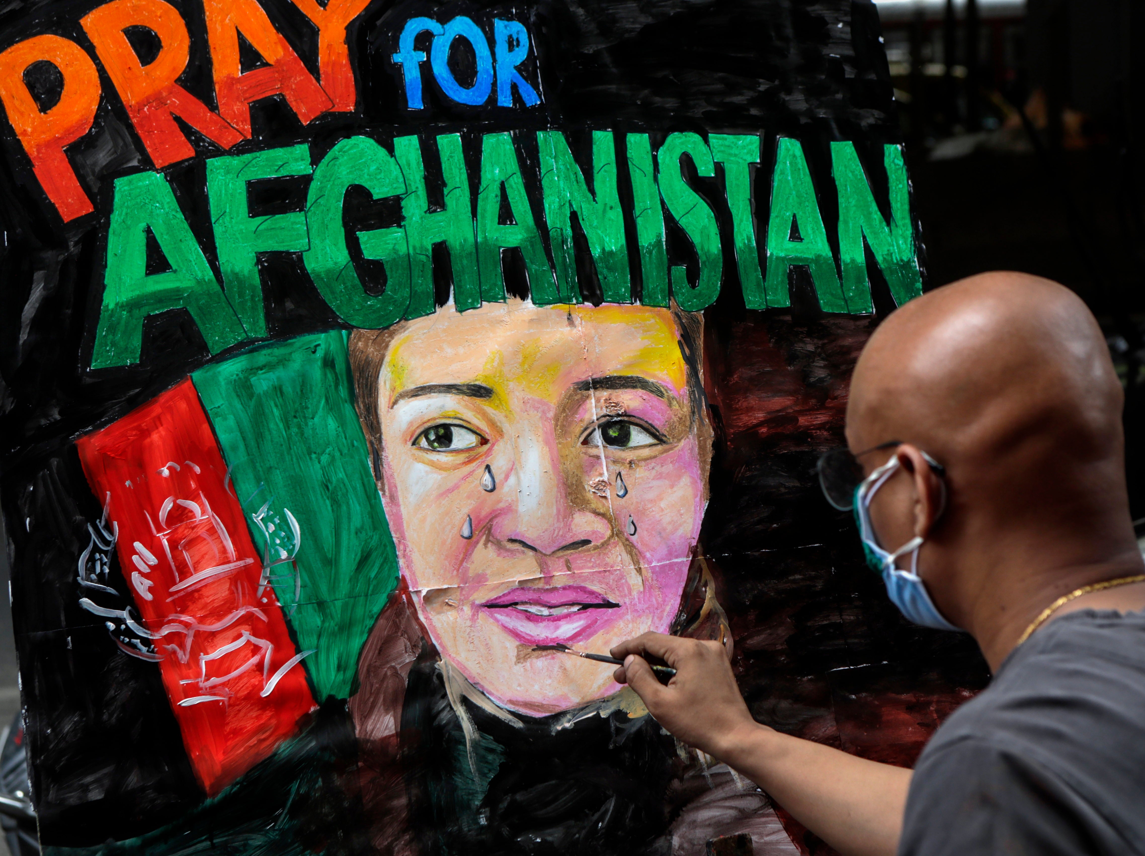 Students of an art school paint messages of solidarity with the people of Afghanistan on a pavement in Mumbai