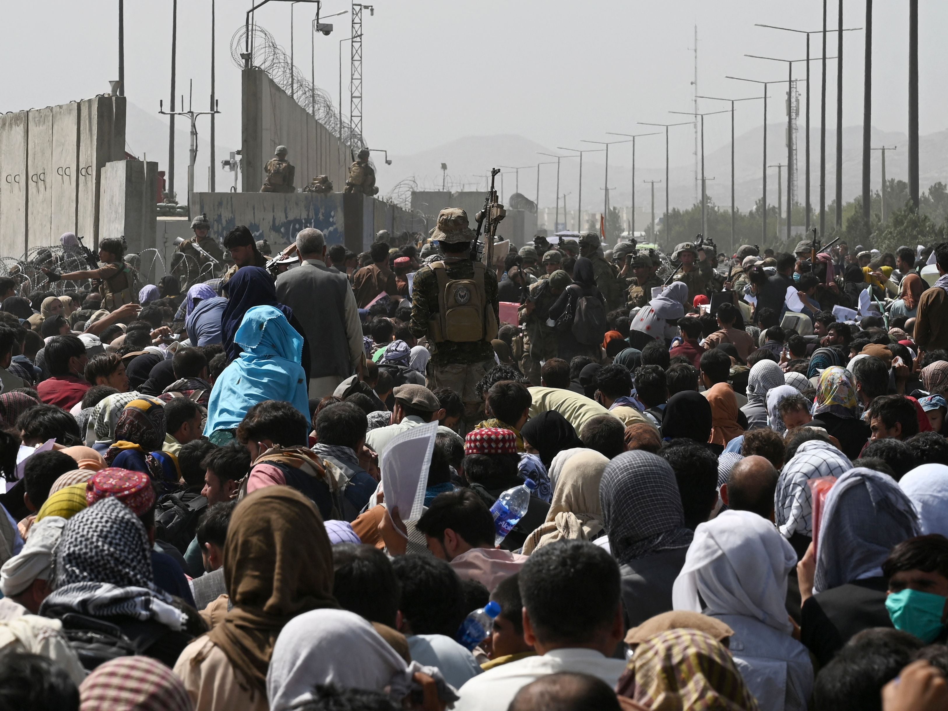 Afghans gather on a roadside near the military part of the airport in Kabul in a desperate bid to leave the country
