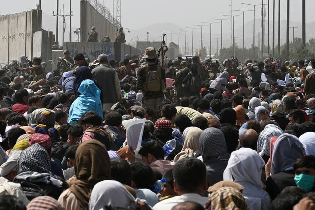 Los afganos se reúnen al borde de la carretera cerca de la parte militar del aeropuerto de Kabul