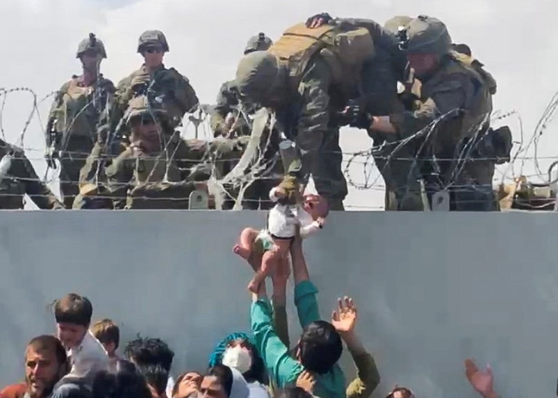 A baby handed over to the US army above the perimeter wall of the airport for it to be evacuated
