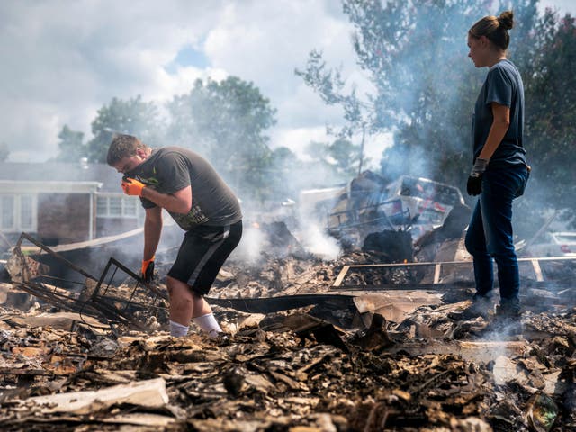 <p>Josh Whitlock and Stacy Mathieson look through what is left of their home after it burned following flooding in Waverly, Tennessee</p>