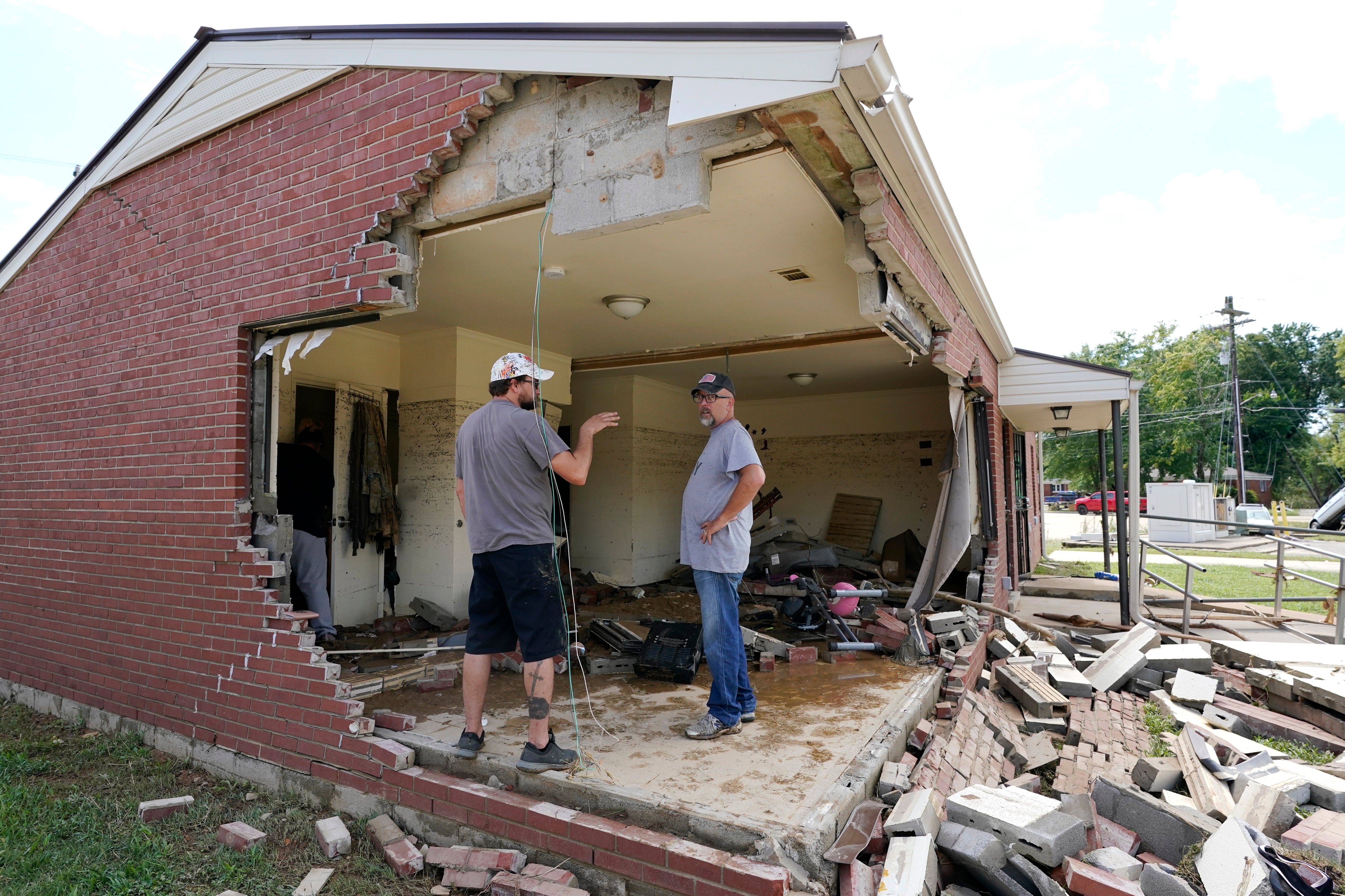 Brian Mitchell, right, looks through the damaged home of his mother-in-law along with family friend Chris Hoover in Waverly on Sunday