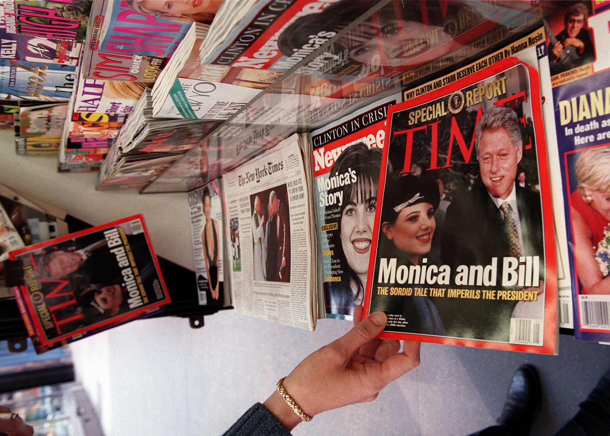 A woman reaches for a copy of Time Magazine on a news stand on 26 January 1998 in New York City