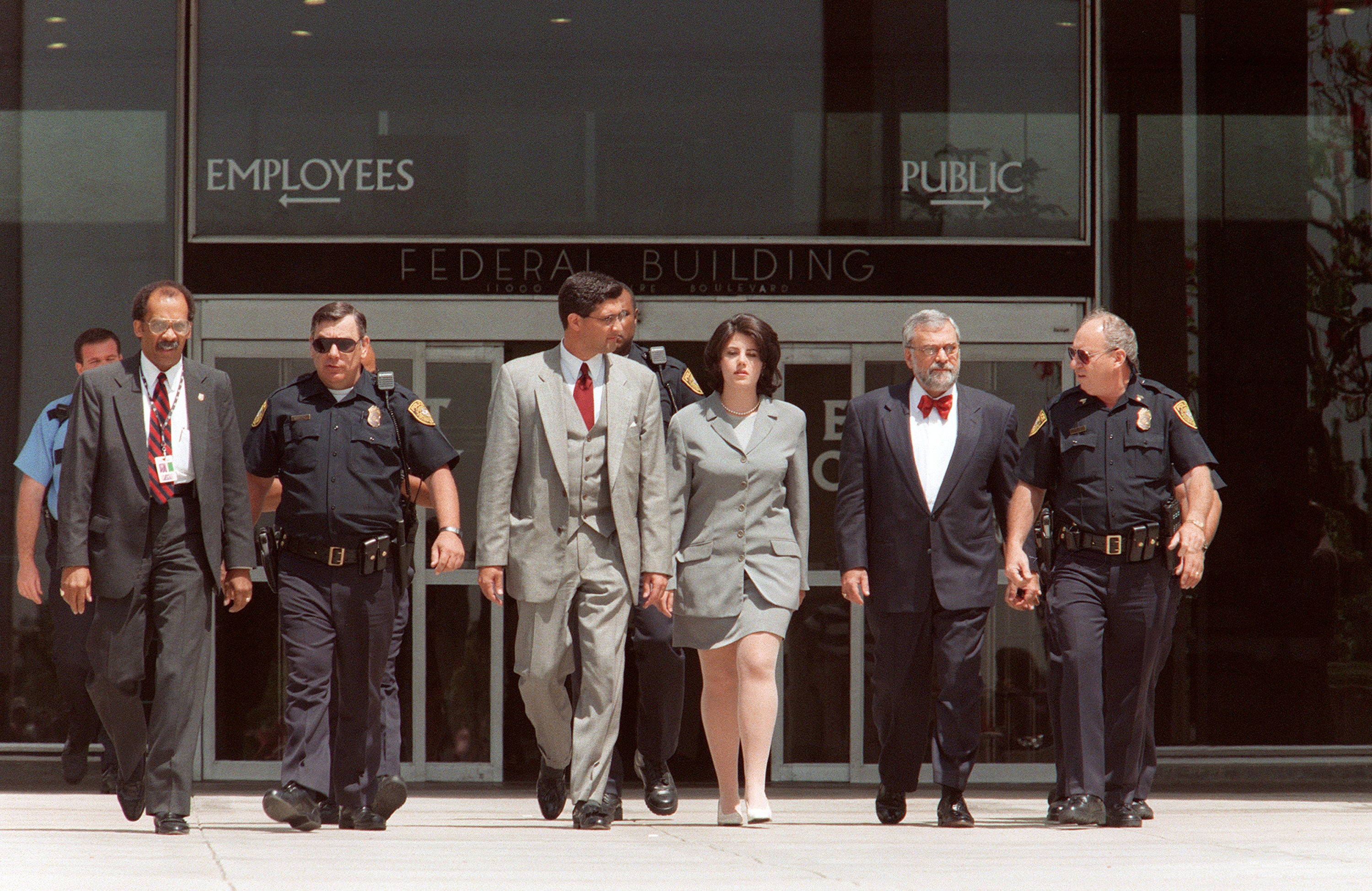 Former White House intern Monica Lewinsky is escorted by police officers, federal investigators and her attorney William Ginsburg as she leaves the Federal Building on 28 May 1998 in Westwood, California, after submitting new evidence to Kenneth Starr's office