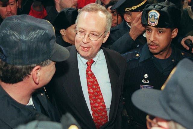 <p>Kenneth Starr, independent counsel, speaks to a Washington, DC police officer as he is escorted away after speaking at a press conference on 22 January 1998</p>