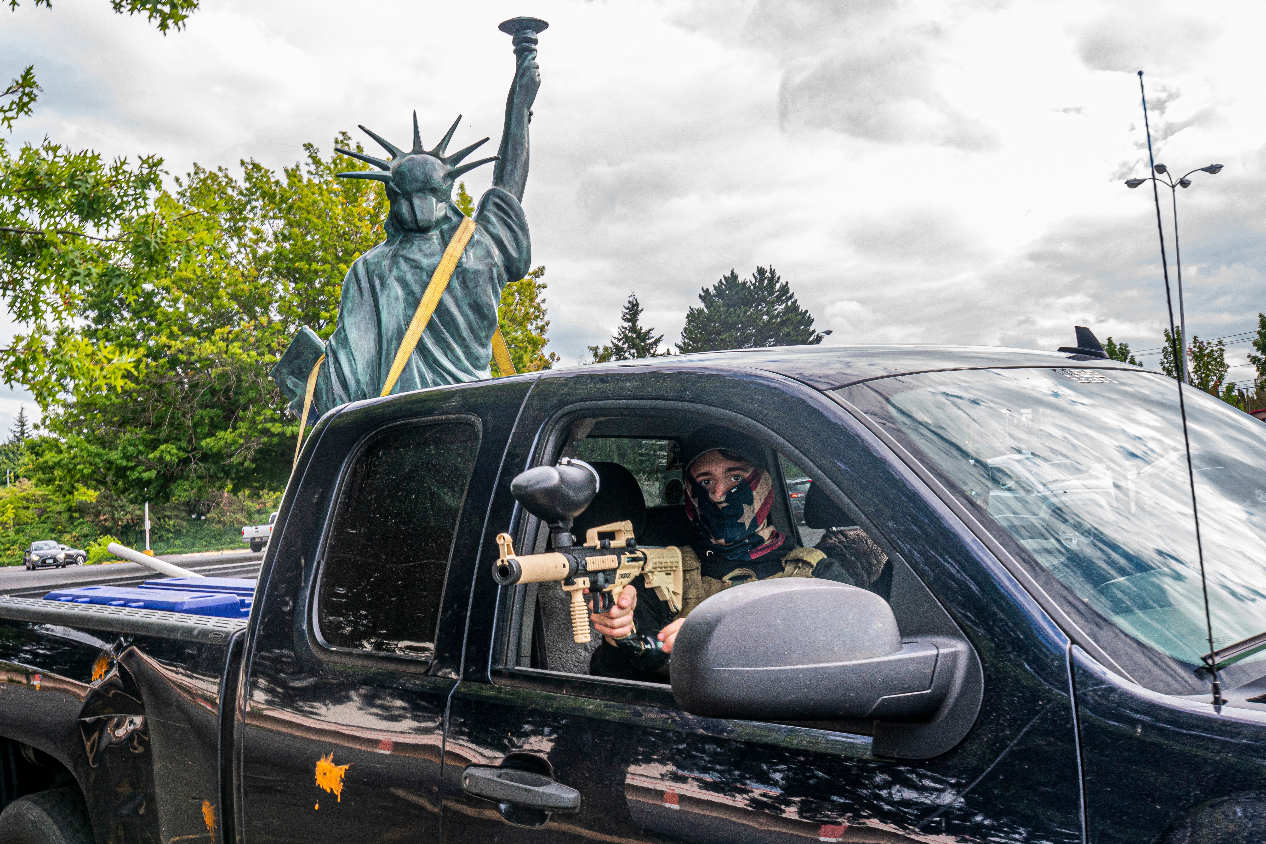 PORTLAND, OR - AUGUST 22: A member of the far-right group Proud Boys aims a paintball gun while leaving a demonstration with a Statue of Liberty replica in the bed of the truck on August 22, 2021 in Portland, Oregon. The Proud Boys and other far-right extremists fought with left-wing activists in Portland on the anniversary of a similar fight in 2020. (Photo by Nathan Howard/Getty Images)